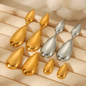 Macro view of gold and silver teardrop earrings on a beige velvet jewelry tray