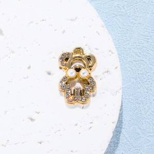 Detailed close-up of a golden alloy bear pendant with white pearls and sparkling rhinestones