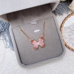 Pink crystal butterfly pendant necklace with gold outlines in a gray jewelry gift box