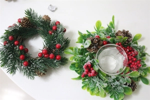 Detail of Christmas candle holder ring with faux pine needles, red berries and snow frosted finish