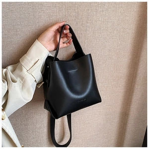 Detail of minimalist black bucket bag with smooth matte leather and branded logo