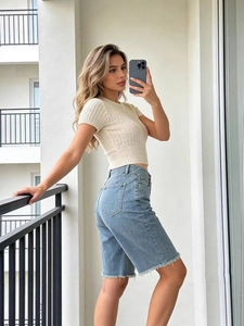 Women's casual beige knit top and blue distressed denim shorts set in sunlight