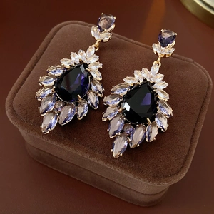Détail de boucles d'oreilles fleur avec cristaux violets sur un support en velours brun