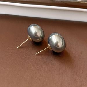Macro shot of large grey high-luster pearls with golden metal pins on textured surface