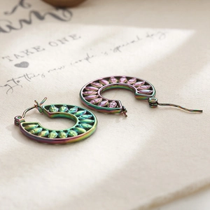 Close-up of rainbow hollowed leaf earrings on a minimalist decorative card base