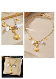Detail of gold ocean-themed necklace with starfish, shells and blue ceramic heart charms