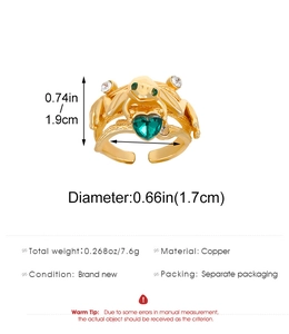 Detail view of gold frog ring with heart green gemstone and adjustable copper band