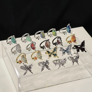 Collection of butterfly rings with enamel finishes and rhinestone details on a display stand