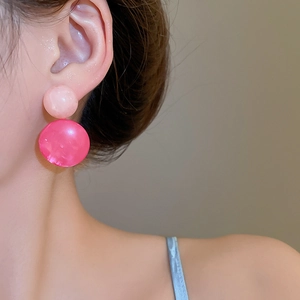 Detailed macro of pink resin ball earrings with marble texture on the earlobe