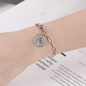 Détail du bracelet avec pendentif pièce reine en argent et fermoir OT sur poignet