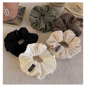 Close-up of five knitted scrunchies in earth tones with refined hollow weave texture