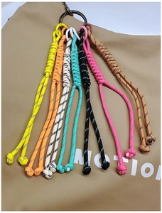 Close-up of colorful braided paracord keychains with plastic carabiners on a canvas bag