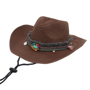 Detail of straw cowboy hat featuring ethnic beads, turquoise stone and pink tassel decoration