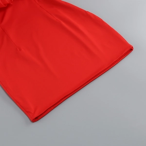 Detailed macro view of the vibrant red bandage dress fabric with refined hemline stitching