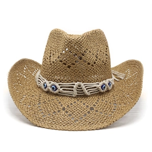 Detail of hand-woven cowboy straw hat featuring bohemian evil eye beads and tassels