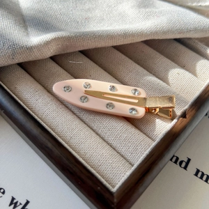 Vue détaillée d'une pince à cheveux rose pâle avec métal doré et strass scintillants