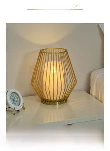 Detail showing a geometric gold metal lantern holder with white LED pillar candle inside