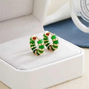Macro detail of gold bamboo-shaped hoop earrings with green enamel on a jewelry box