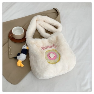 Detail of white plush donut bag with Sweet embroidery and bird charm on bed