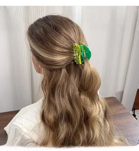 Detailed close-up of a green butterfly hair claw clip with red accents on half-up hair