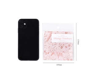 Detail of pink embossed flower sticker pack with size markers and phone for scale