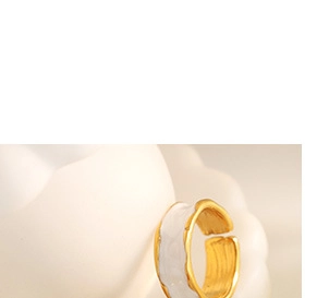 Macro detail of gold-plated open ring featuring white enamel and wavy edges