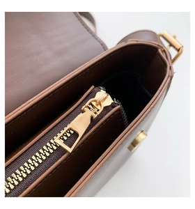 Detail shot of the brown shoulder bag's interior featuring a golden metal zipper pocket