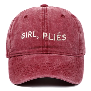 Détail de la broderie GIRL PLIÉS sur une casquette de baseball vintage rouge délavé