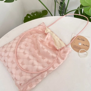 Gros plan détaillé de la dentelle rose brodée et du motif matelassé du sac cabas