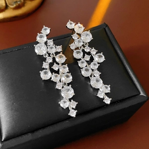 Macro detail of silver drop earrings featuring irregular zircon clusters and tassel design
