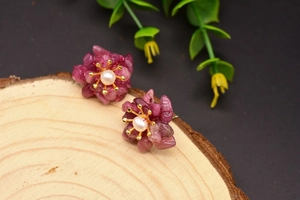 Detailed shot of floral pearl earrings with pink stone petals on a wooden background