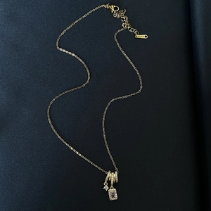 Collier en acier inoxydable doré avec pendentif cristal et anneaux en zircon sur tissu bleu
