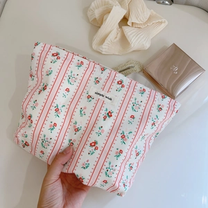 Détail de trousse à maquillage en coton à fleurs, rayures rouges et étiquette tissu