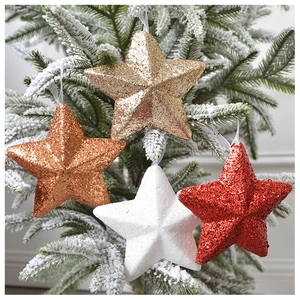 Close-up of sparkling sequined star ornaments hanging on a snowy Christmas tree branch