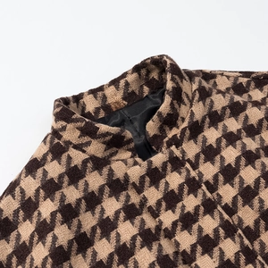 Detailed view of the stand collar and houndstooth pattern on the tweed jacket