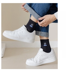 Detail of black crew sock with embroidered smiley face and NICE text paired with jeans