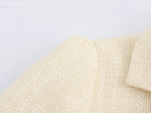 Primo piano della trama in tweed beige che mostra dettagli eleganti del tessuto