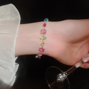 Silver bracelet with colorful square zircon stones worn by a model holding a glass