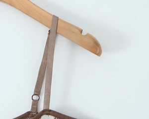 Detail des braunen Strick-Karokleids mit dünnen Trägern auf einem Holzbügel