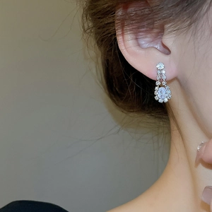 Close-up of elegant silver teardrop earrings with sparkling crystal pavé on model