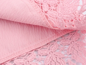 Macro view of pink dress fabric showing delicate lace stitching and pleated texture
