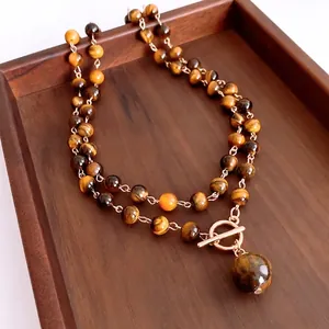 Tiger eye stone double-layer necklace with golden toggle clasp on a dark wooden tray