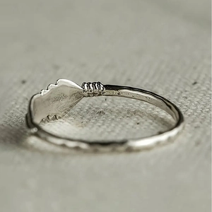 Macro-opname van een zilveren ring met gehamerde textuur en bladvormig vintage ornament