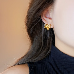 Gros plan sur des boucles d'oreilles nœud plaquées or 18 carats portées par un mannequin
