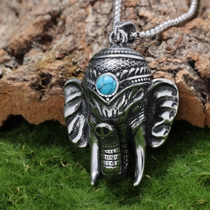 Gros plan détaillé d'un pendentif éléphant argenté avec turquoise sur bois moussus