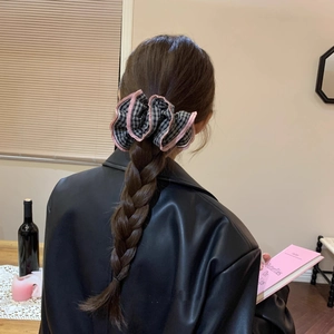 Close-up of a large black and white checkered fabric scrunchie with pink edges on hair