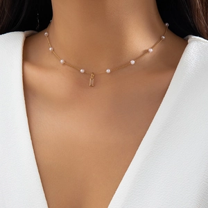 Close-up of gold layered necklace with small pearls and a clear rectangular pendant