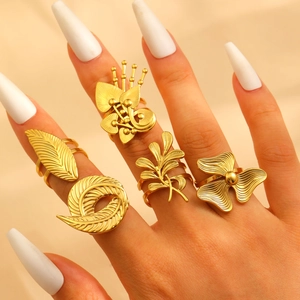 Macro detail of gold-plated leaf and feather rings showing fine brushed texture and craftsmanship