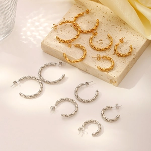 Twisted stainless steel hoop earrings in gold and silver, multiple sizes on stone base