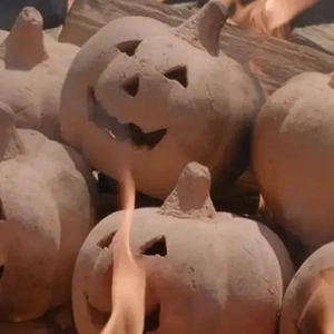 Macro view of heat resistant ceramic pumpkin heads stack in fire pit for Halloween decor